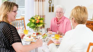 Drei Frauen sitzen am Tisch und essen Kuchen.