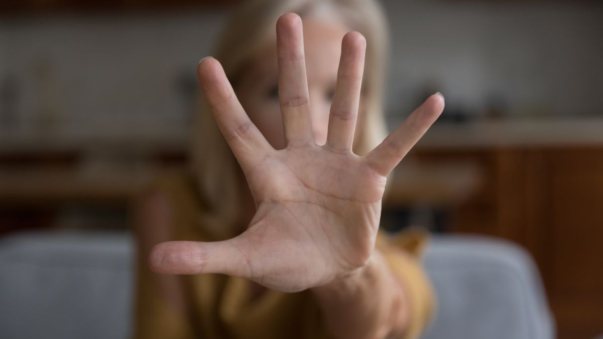 Eine ältere Frau streckt die geöffnete Hand in Richtung Kamera aus.