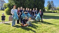 Gruppenfoto mit insgesamt 13 Kindern, Jugendlichen und ehrenamtlichen Gruppenleitungen, die 5 Müllsäcke hochhalten, die sie bei der Clean-Up Aktion gesammelt haben.