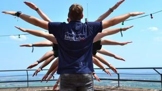 Kinder hintereinander mit ausgebreiteten Armen