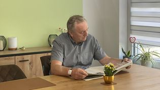 Ein Senior mit einem Hausnotruf-Armband beim Zeitunglesen