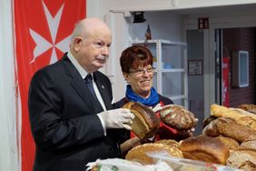 Fra`Giacomo hilft bei seinem Besuch im Herbst 2019 den Ehrenamtlichen der Pulheimer Malteser Tafel mit der Ausgabe von Lebensmitteln an Bedürftige. Foto: Malteser Köln