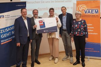 Fünf Personen vor Bannern, eine Urkunde mit dem Darmkrebssiegel 2023 wird gezeigt.