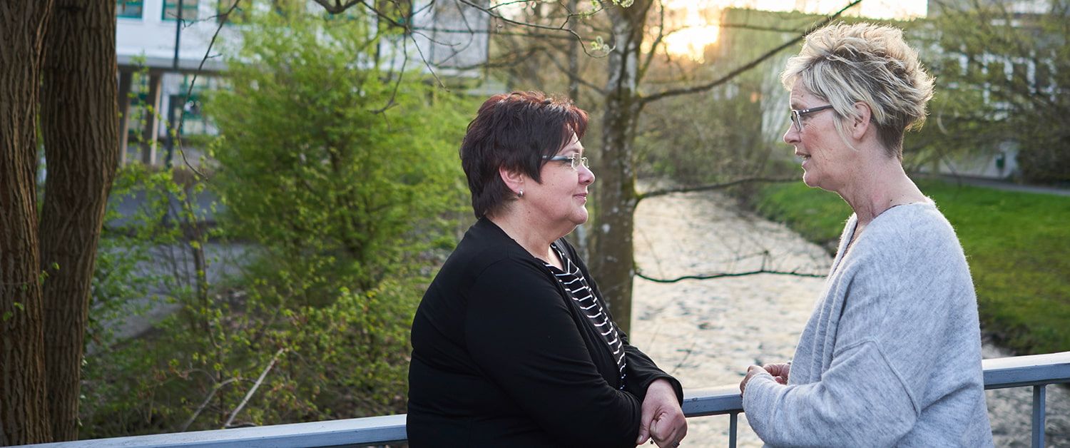 Trauerbegleitung: Zwei Frauen stehen auf einer Brücke und unterhalten sich. 