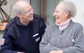 Ein Ehrenamtlicher spricht mit einer älteren Dame 