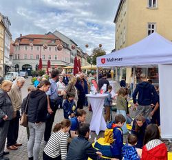 Auf dem Domplatz in Fulda steht eine Menschentraube am Info-Stand der Malteser. Foto: Malteser