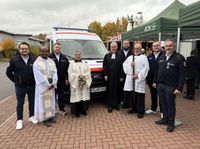 Vor dem neuen Katastrophenschutzfahrzeug der Malteser stehen acht Personen nebeneinander. Sie freuen sich über die Segnung des Fahrzeugs. Von links nach rechts: Christoph Wagner (Wachleiter Jesberg/Gilserberg), Pater Simon (Herz-Jesu-Gemeinde Fritzlar), Constantin Mühr (Bereichsleiter Malteser Rettungsdienst Nord), Messdienerin Angelika Lippert, Pfarrer Gunnar Hartmann (evangelische Kirchengemeinde Gudensberg), Messdiener Wolfgang Lippert, Felix Siegel (Wachleiter Gudensberg) und Markus Schips (Geschäftsführer Malteser Rettungsdienst Hessen).
