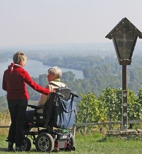 Zwei Frauen sprechen miteinander. Die rechte Dame sitzt im Rollstuhl. 