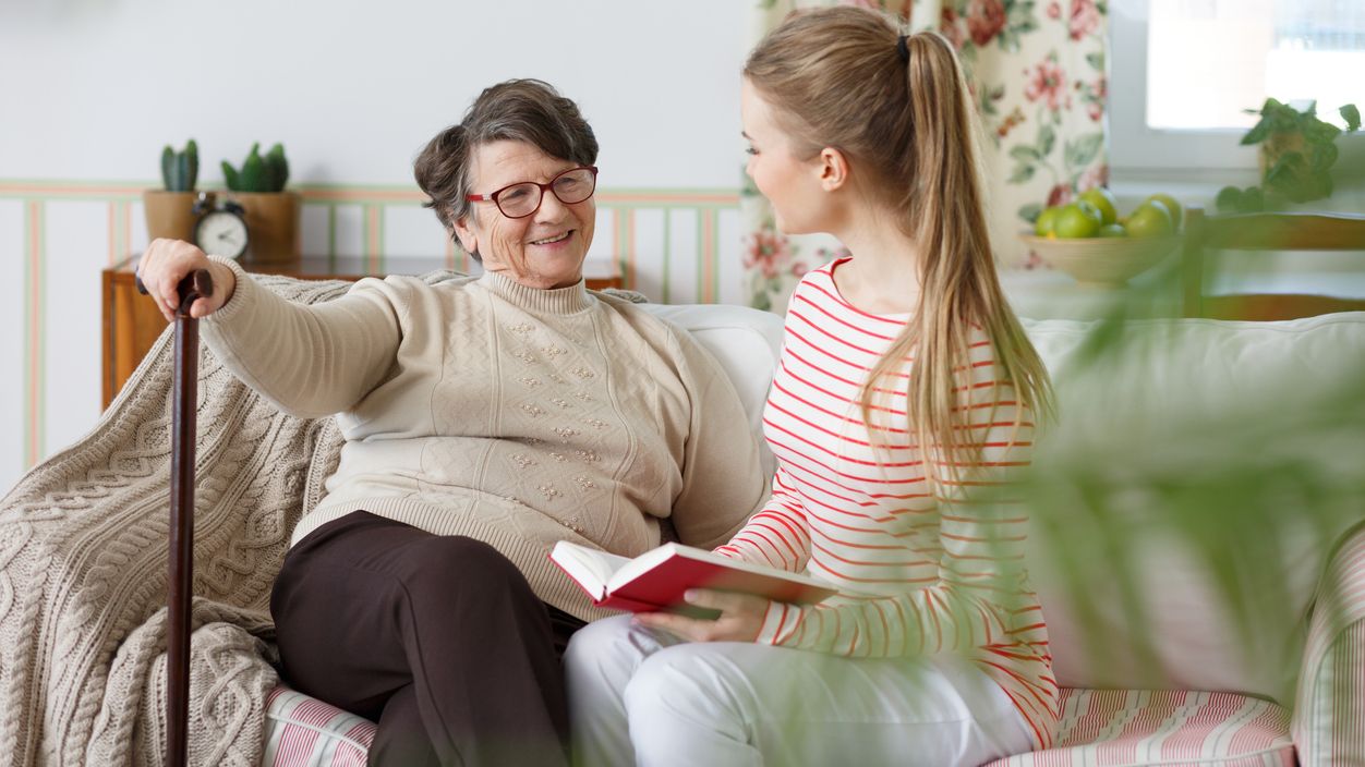 Eine junge Frau liest einer älteren Frau ein Buch vor