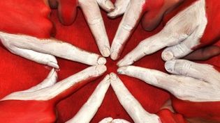 4 Menschen formen mit ihren Händen das achtspitzige Kreuz der Malteser