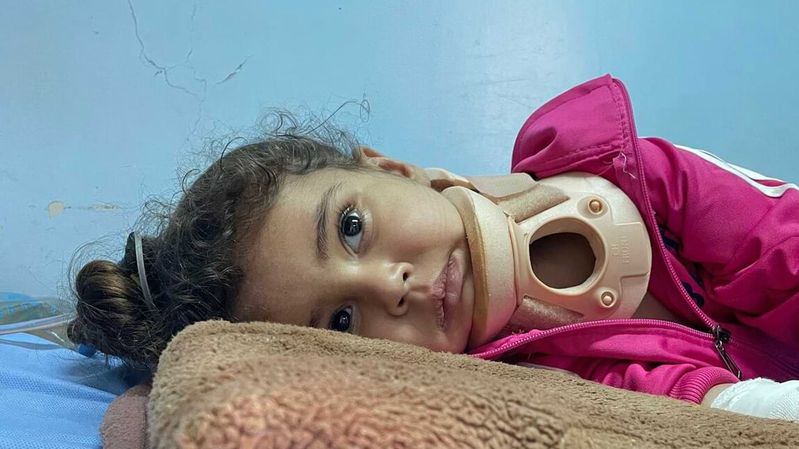 Ein auf der Seite liegendes kleines Mädchen mit einer Halskrause aus Kunststoff. 