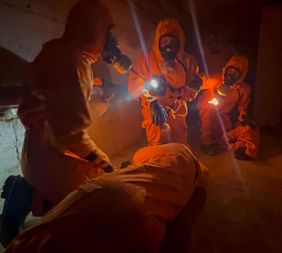 Malteser Ehrenamtliche üben mit Schutzausrüstung das sichere Betreten kontaminierter Bereiche.