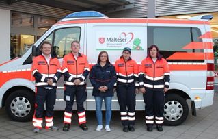 Menschen in Malteser Einsatzkleidung vor dem Malteser Herzenswunschkrankenwagen