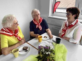 Drei Frauen am Tisch unterhalten sich