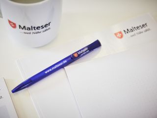 Kugelschreiber, Tasse und Papier mit Malteser Logo