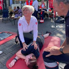 Eine Frau übt die stabile Seitenlage mit einer jungen Frau.