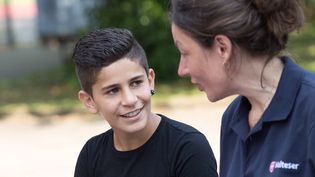 Eine junge Malteser Integrationslotsin unterhält sich mit einem Jungen.