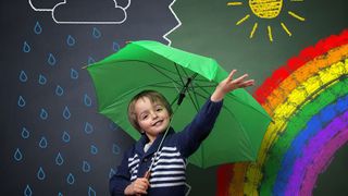 Junge mit einem Regenschirm vor einem gemalten Regen-Sonnenschein-Bild
