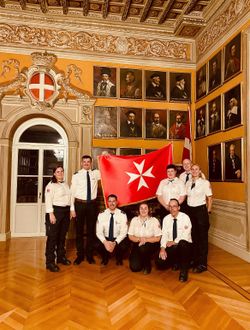 Die Ehrenamtlichen halten eine Malteser Flagge hoch