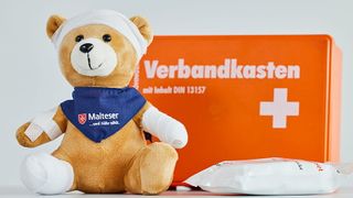 Erste-Hilfe-Verbandskasten mit Teddy, der verbunden und gepflastert ist