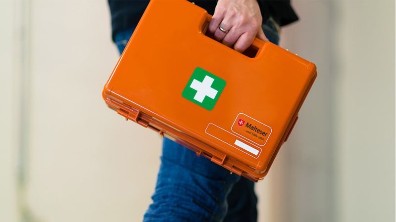 Mann trägt Erste-Hilfe-Kasten