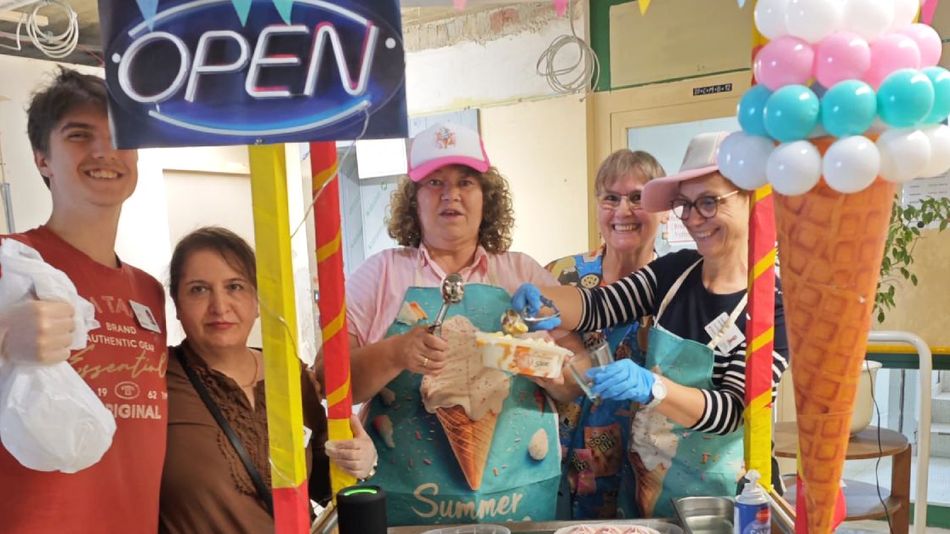 Eine Gruppe von fünf Menschen hinter einem Eisstand mit Luftballons.