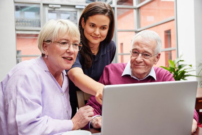 zwei Seniorinnen und eine Kursleiterin blicken auf einen Computerbildschirm. 