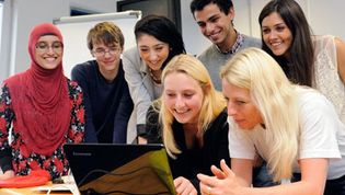 Mehrere Menschen schauen gemeinsam auf ein Laptop