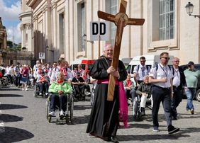 Eine Menschengruppe geht hinter dem Kreuz. Foto: Jochmann