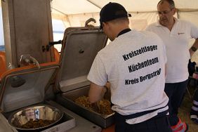 Ein Koch vom Küchenteam bereitet veganes Gyros zu. Ein anderer Malteser sieht dabei zu (Foto: Malteser Viernheim)