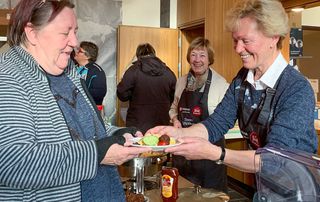 Eine Frau schenkt einer anderen Frau eine warme Mahlzeit aus.