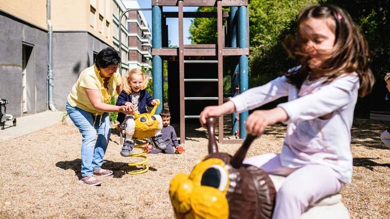 Kinder und eine Betreuerin auf einem Spielplatz