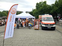 Einsatzfahrzeuge der Malteser mit einem Ausgabestand für Essen und einer Fahne der Tafel