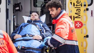 Notfallsanitäter transportiert einen Patienten auf einer Trage in den Rettungswagen.