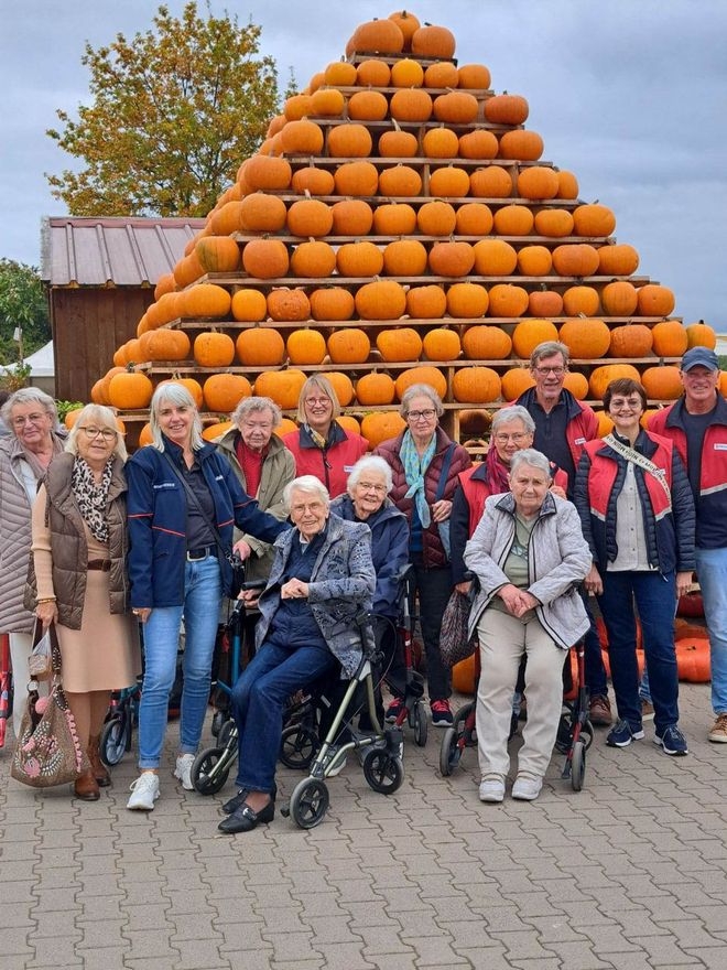 Die Ausflugsgruppe posiert vor einer fast vier Meter hohen Pyramide aus kräftig orangen Kürbissen