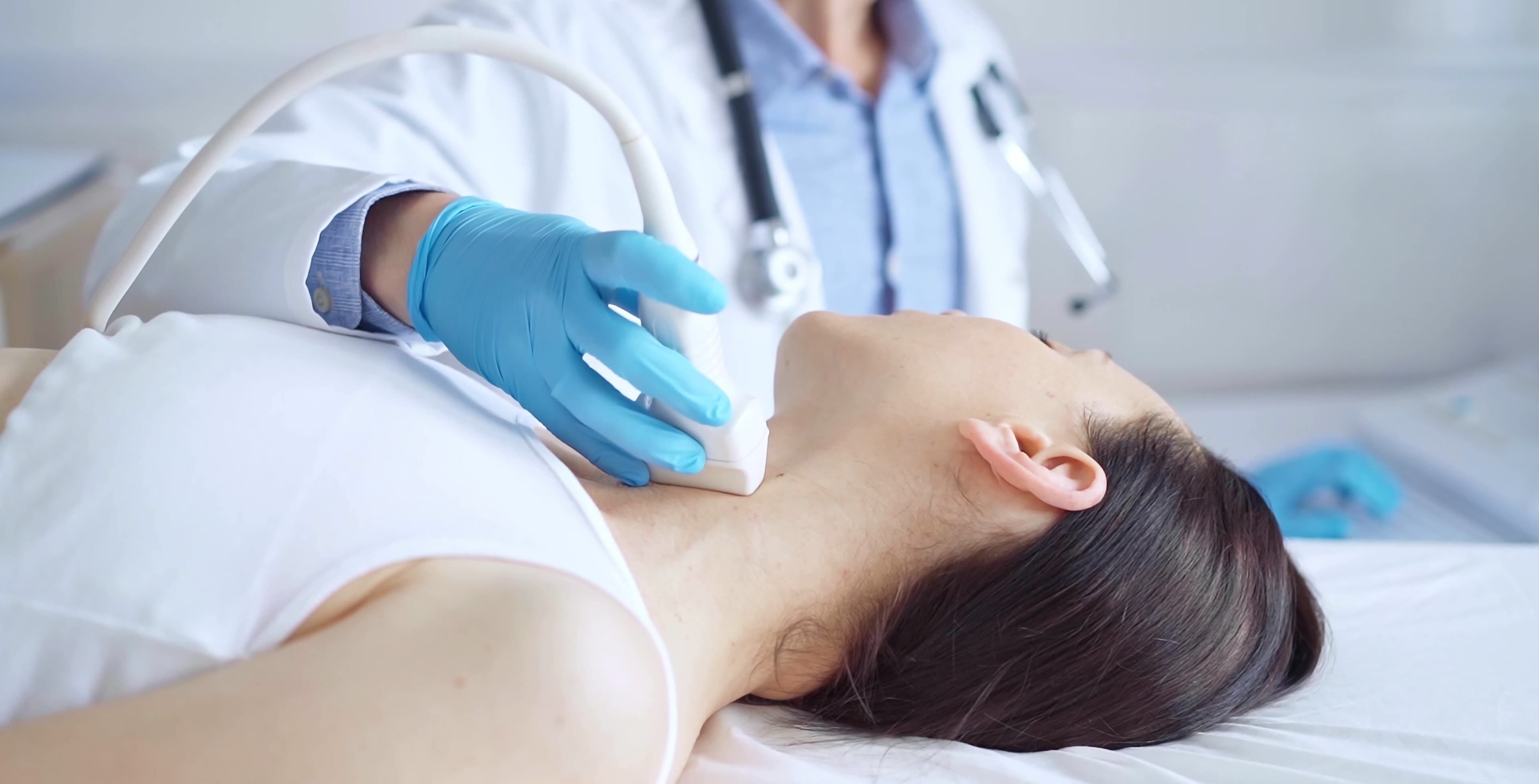 Arzt führt eine Ultraschalluntersuchung der Schilddrüse bei einer Patientin durch.