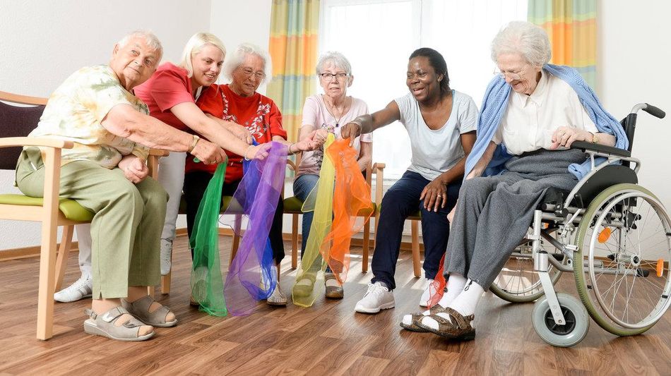 Ältere, sitzende Frauen halten bunte Tücher.
