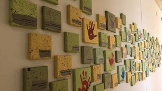 An einer Wand hängen Bilder mit Handabdrücken