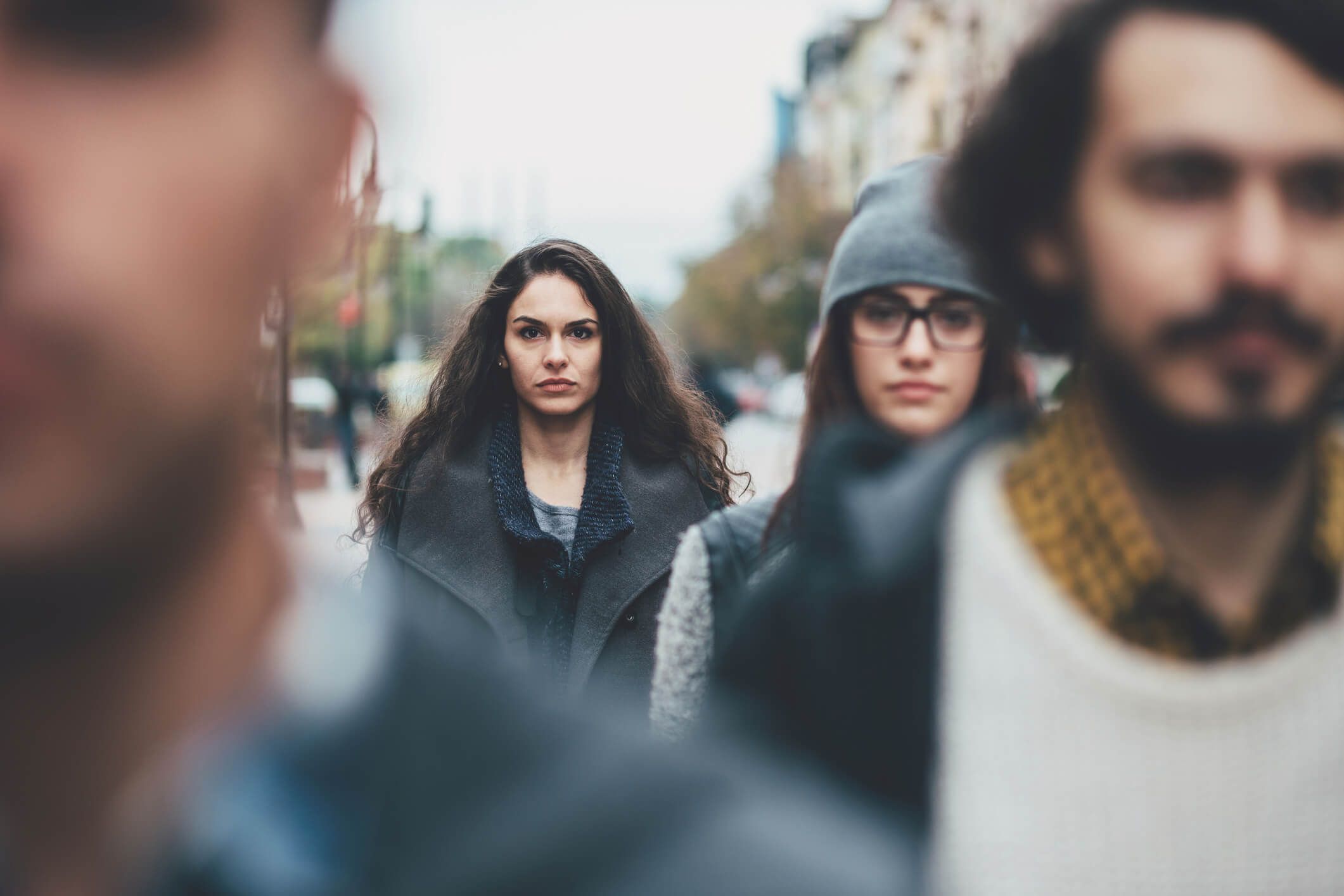 Eine junge Frau sieht unglücklich aus in einer Gruppe junger Menschen