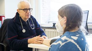 Ein Arzt untersucht ein Kind, das eine FFP2-Maske trägt. 