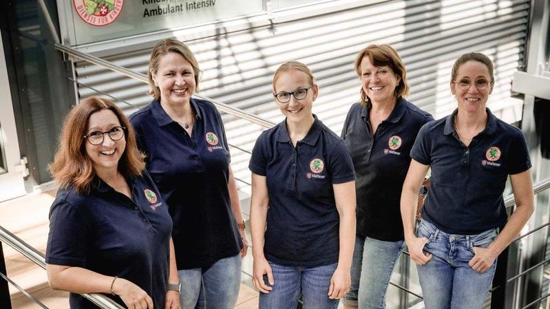 Fünf Mitarbeiterinnen des Malteser-Kinderintensivpflegedienstes stehen gemeinsam auf einer Treppe.
