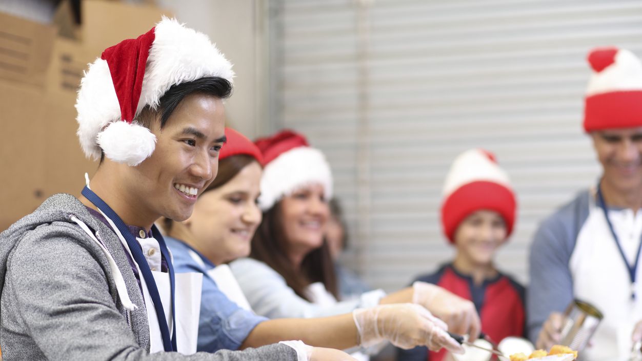 Menschen mit Weihnachtsmützen geben Essen an Bedürftige aus