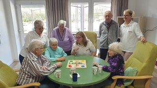Bewohner spielen ein Spiel und sitzen gemeinsam am Tisch