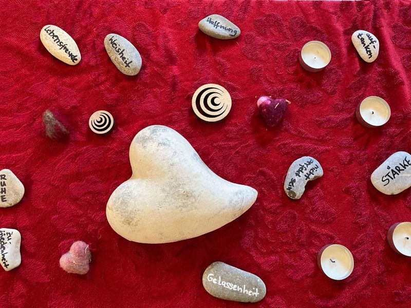 Tisch mit rotem Tischtuch, darauf Steine mit Wörtern