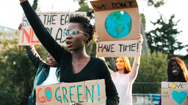 Junge Menschen demonstrieren mit Schildern aus Pappe.