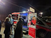 Interessierte informieren sich neben einem Roll-Up und vor dem neuen Herzenswunsch-Krankenwagen über den Dienst