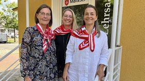 Drei Frauen stehen auf den Stufen einer Treppe und blicken freundlich in die Kamera.