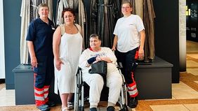 Eine Frau im Rollstuhl und drei Begleiterinnen vor Figuren, die Kostüme der Oberammergauer Passionsspiele tragen.