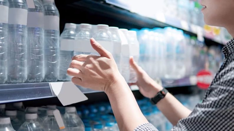 Eine Nahaufnahme: Eine Frau kauft Wasser im Supermarkt.