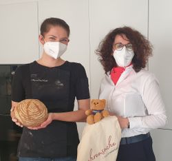 Zwei Frauen zeigen ein Brot für den guten Zweck